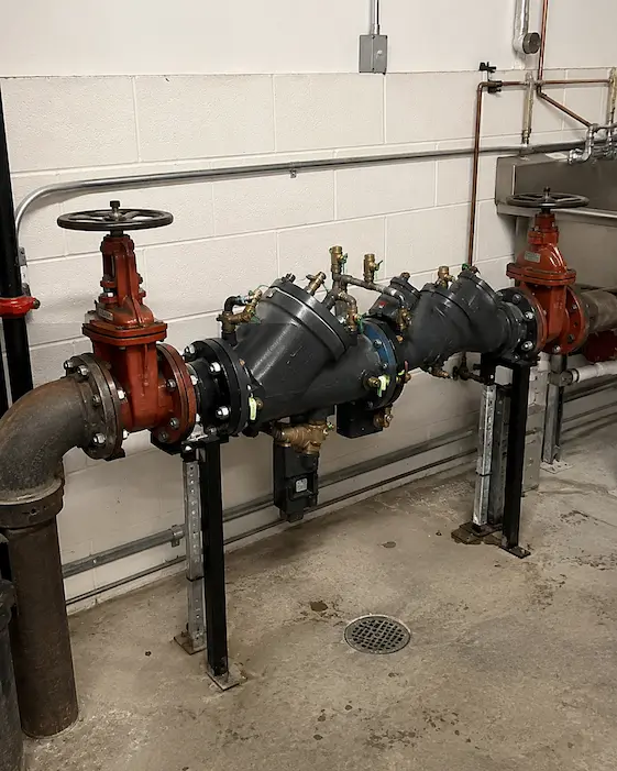 Commercial backflow prevention assembly inside a Northwest mechanical room with shutoff valves, test ports, and industrial water piping for Elite Mechanical backflow testing.